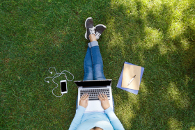 Top view of female student sitting in park with laptop